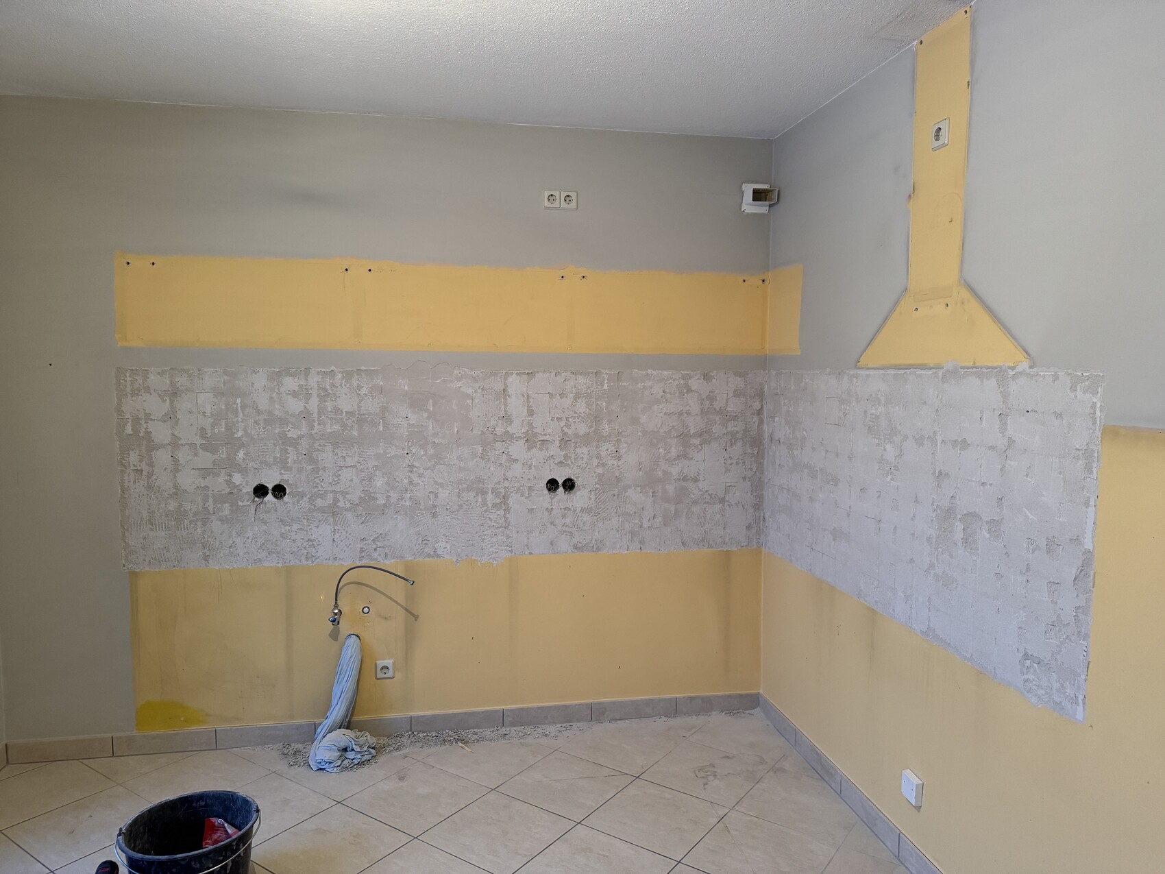Küche im Umbau: Wände freigelegt, gelbe Isolationsstreifen, Installationen sichtbar.
