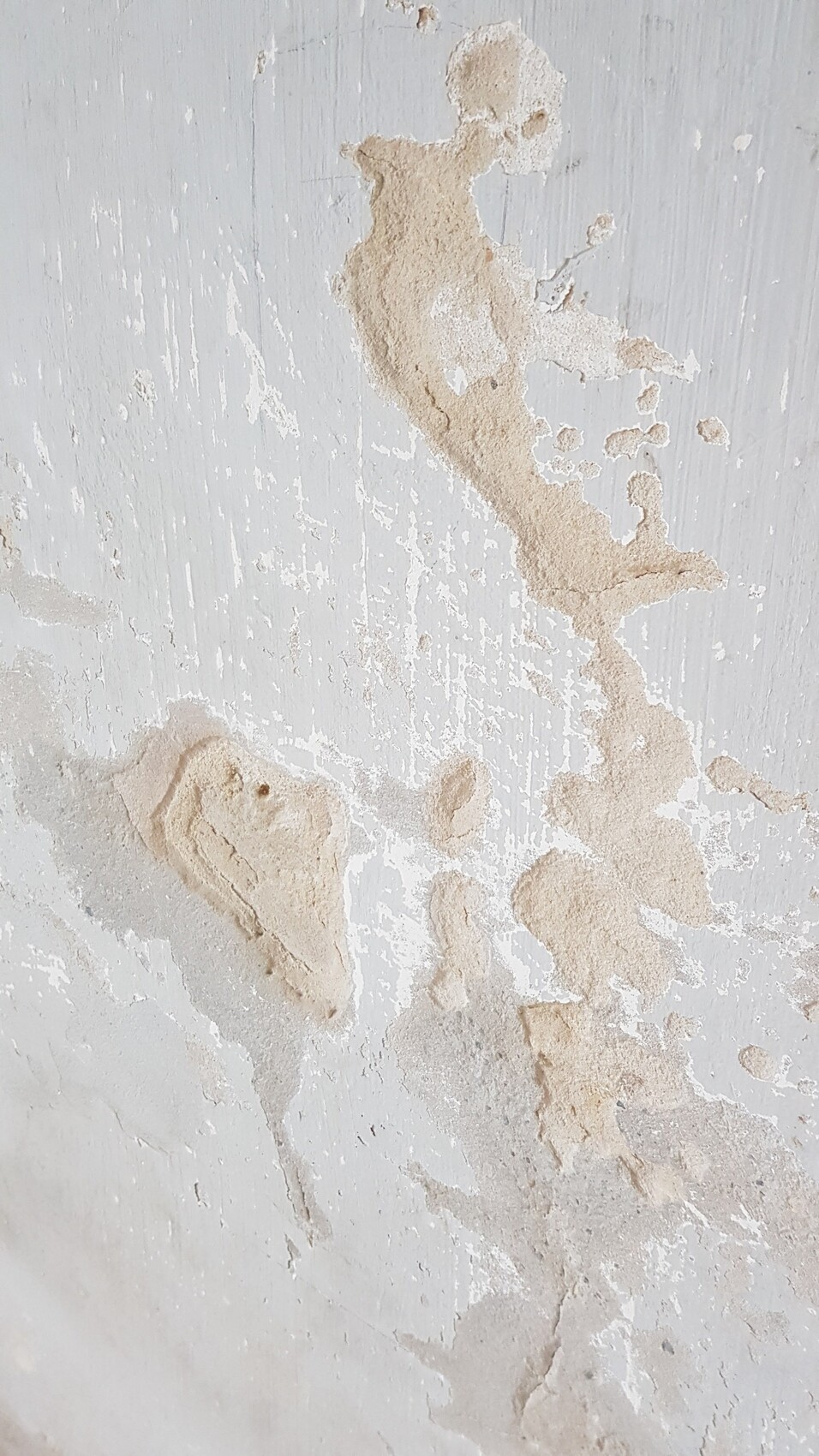 Wand mit abgeblättertem Putz; beige Flecken auf weißer Oberfläche.