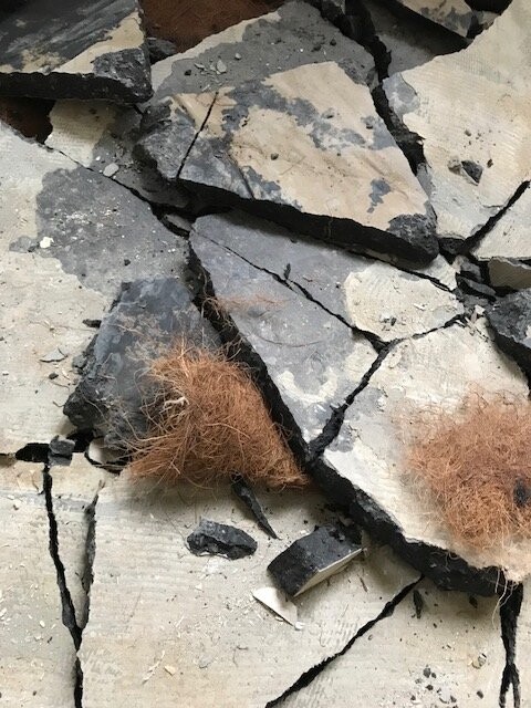 Zerbrochene Betonplatten und Bauabbruch-Schutt mit Daemmfasern.