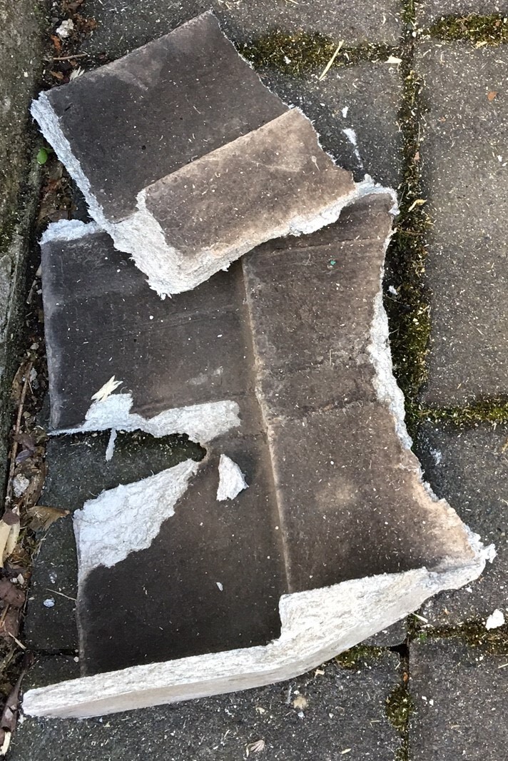 Zerbrochene Betonplatten mit Putzresten auf gepflastertem Boden