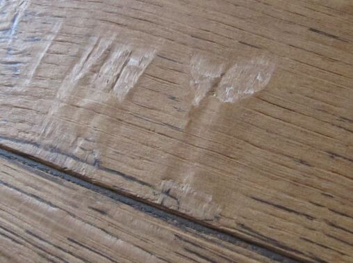 Holzoberfläche aus zwei Planken mit Kratzern und hellen Flecken.