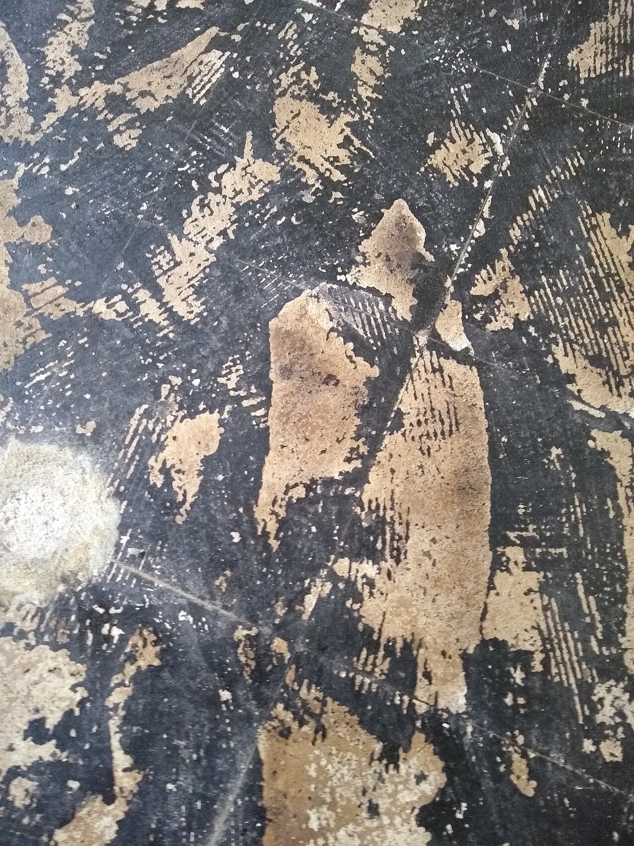 Nahaufnahme einer abblätternden Farbe auf einer dunklen Betonoberfläche mit Rissen