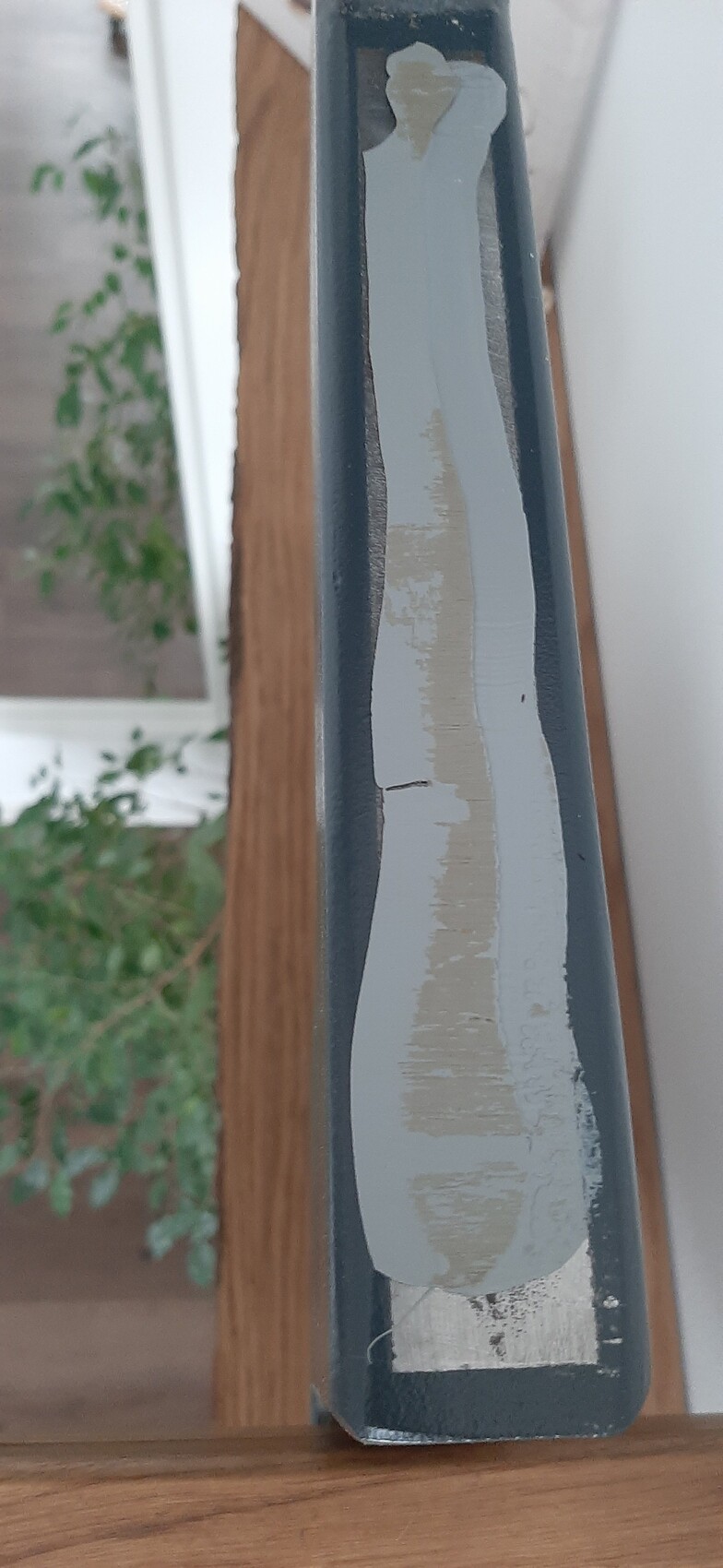 Nahaufnahme einer Türrahmenkante mit abgeplatzter grau-beiger Farbe.