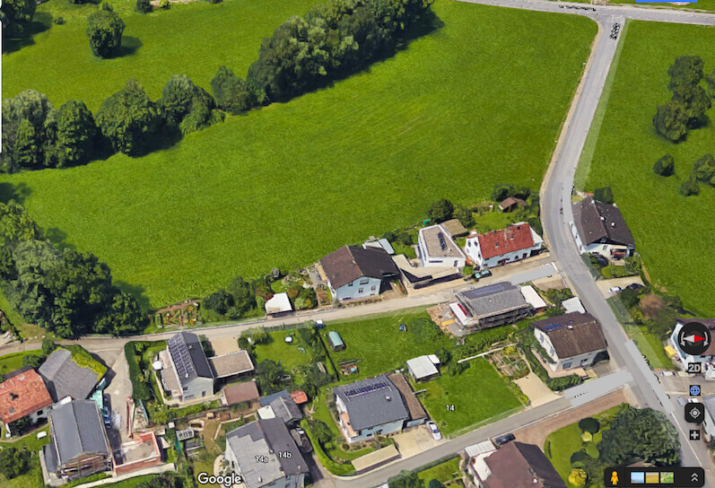 Luftbild eines kleinen Dorfes mit Häusern, Straßen und Grünflächen.