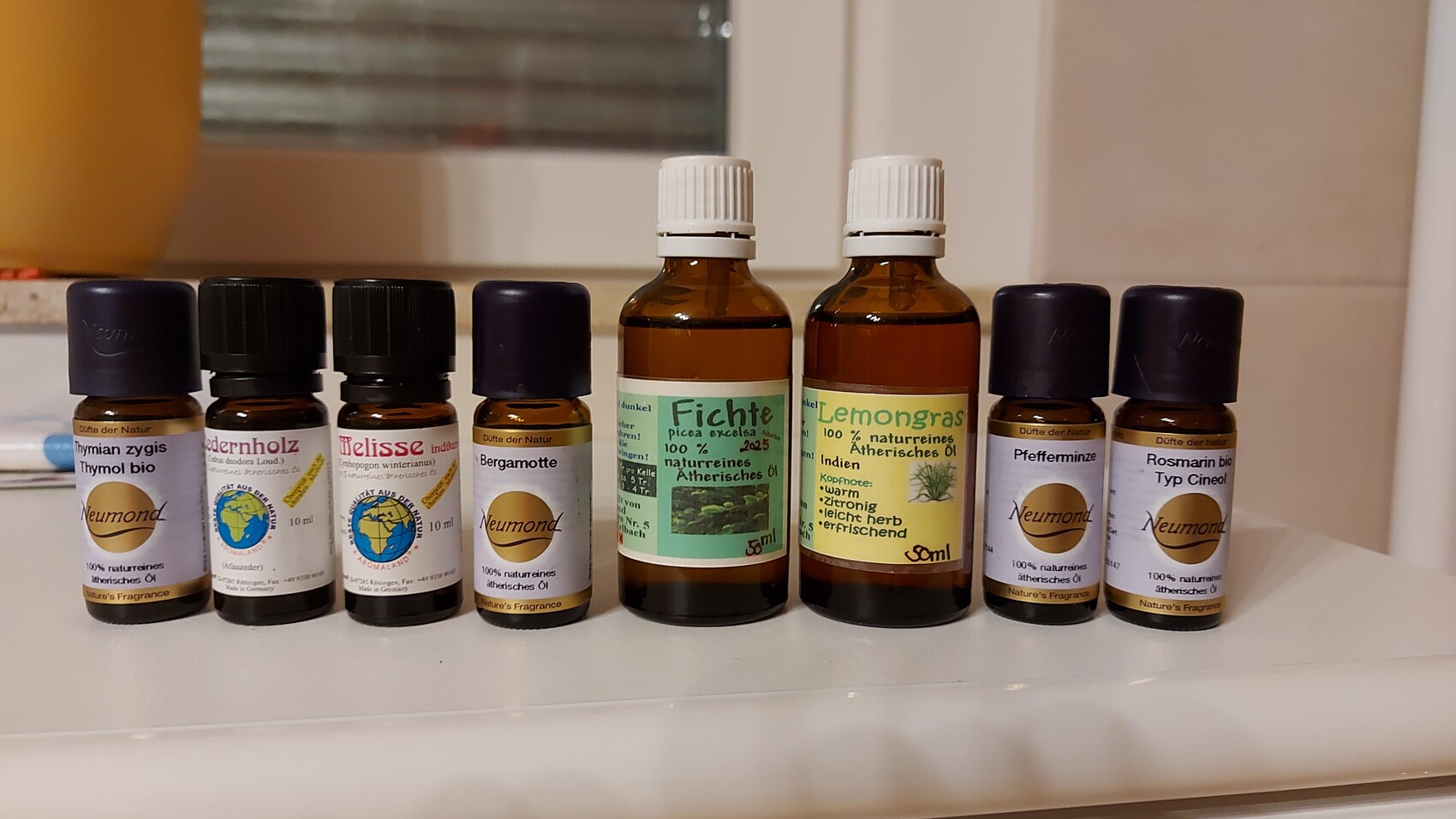 Mehrere braune Flaschen ätherischer Öle stehen auf einer weißen Ablage.