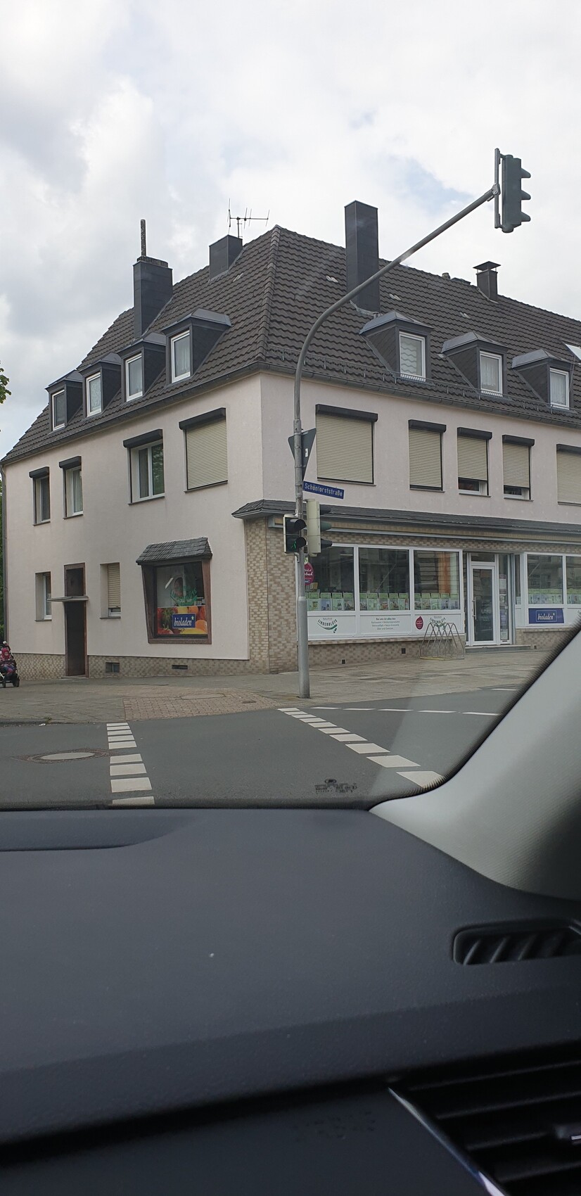 Eckhaus mit Ladenfronten im Erdgeschoss, Wohnräume darüber; Straßenszene aus dem Auto.