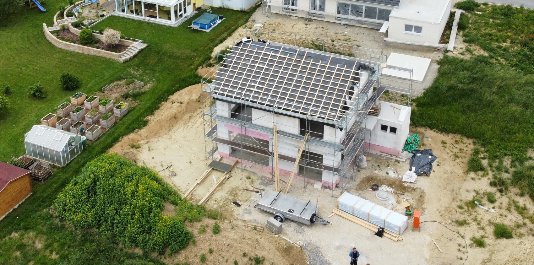 Vogelperspektive: Rohbau eines zweistöckigen Hauses mit Gerüst und Dachkonstruktion.