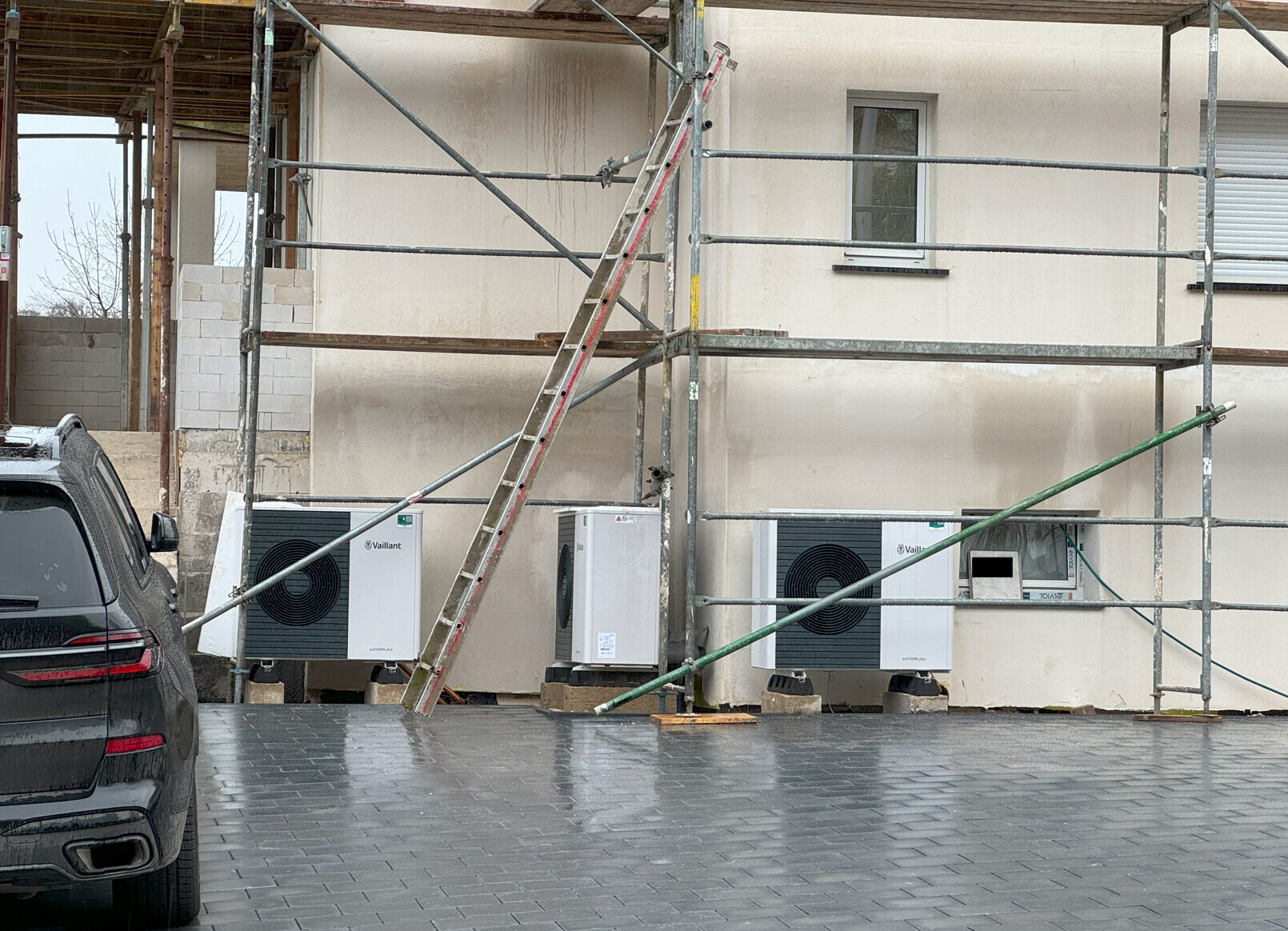 Baugerüst an einer Villa unter Renovierung, zwei Klimageräte (Vaillant), Leiter, Auto links.