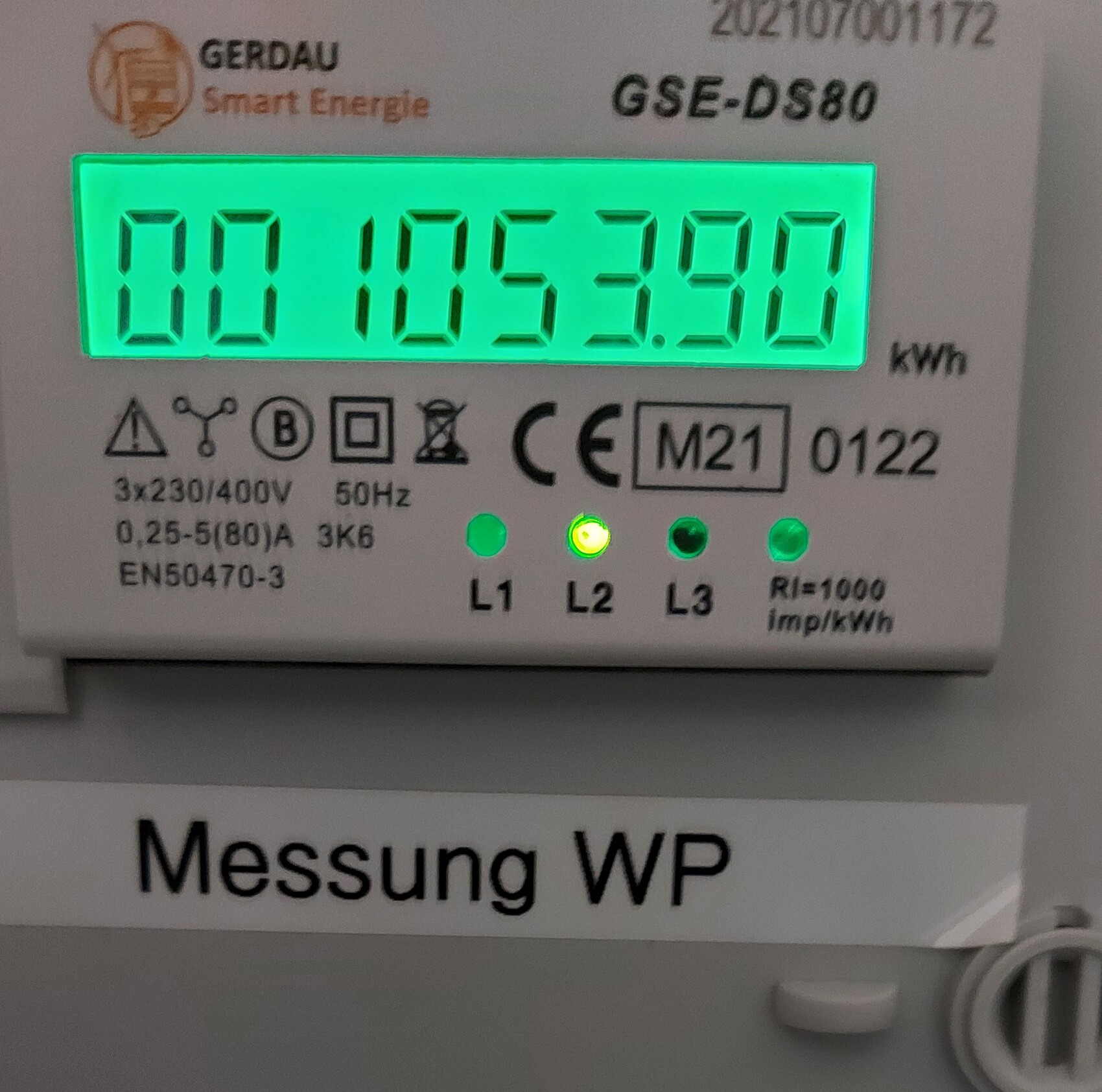 Elektrischer Zähler mit grünem Display zeigt 1053.90 kWh; drei LEDs L1–L3.