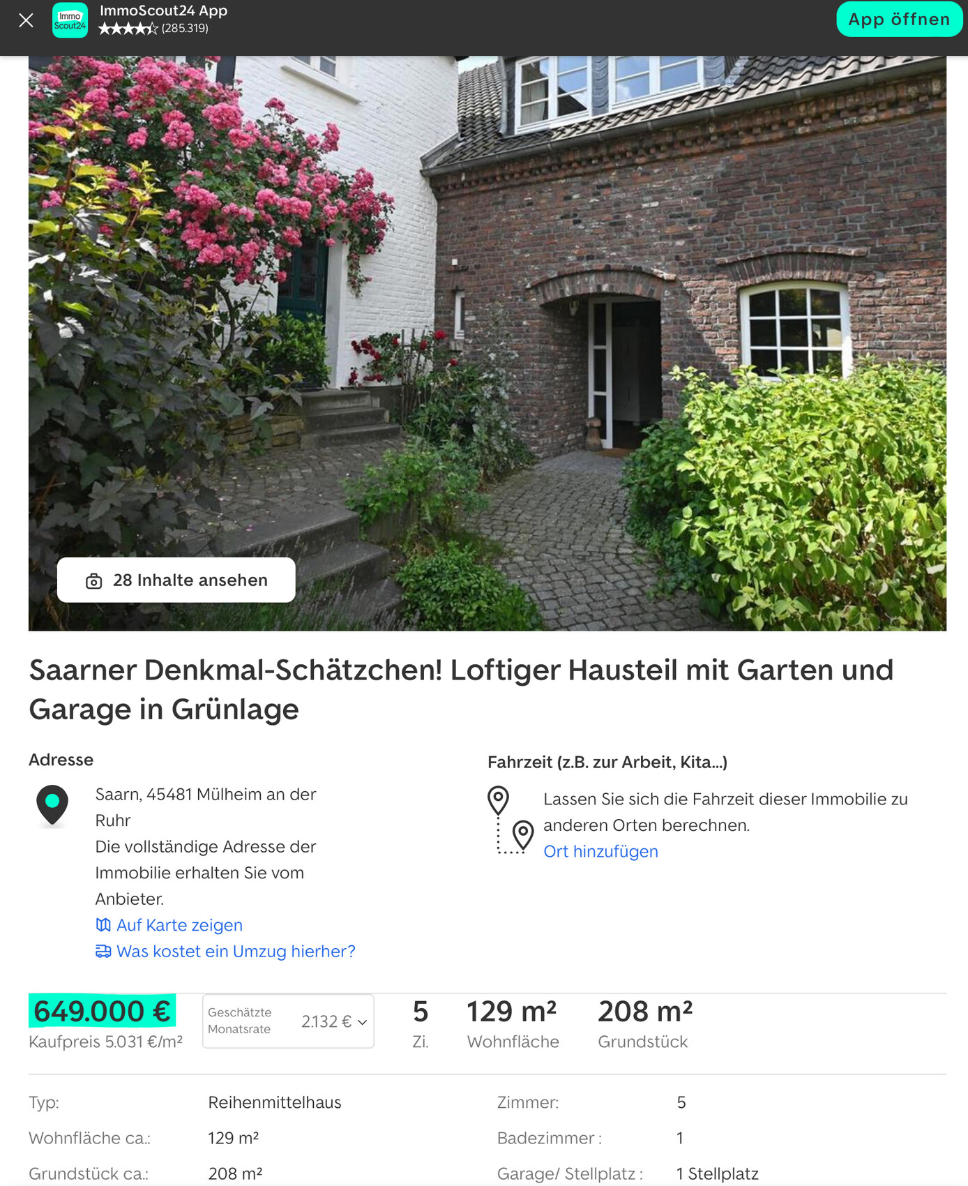 Vorgartenweg aus Pflastersteinen vor rotem Backsteinhaus mit Bogen-Eingang und Rosen.