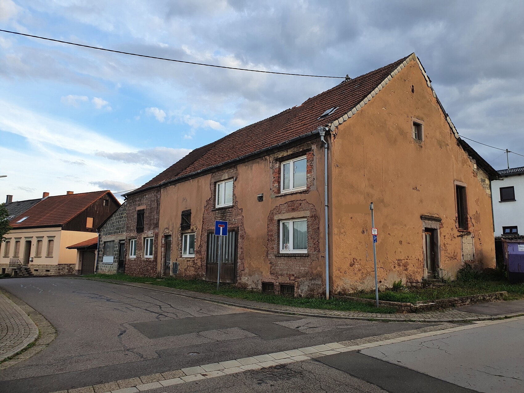 Straßenansicht alter Häuser mit bröckelnder Putzfassade und Straßenumgebung.