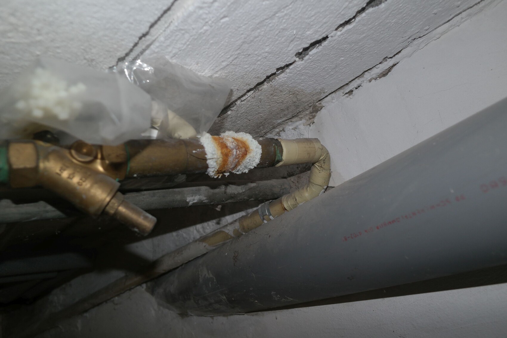 Kupferrohr mit Messingfitting, weiße Krusten an der Verbindung; daneben ein graues Rohr.