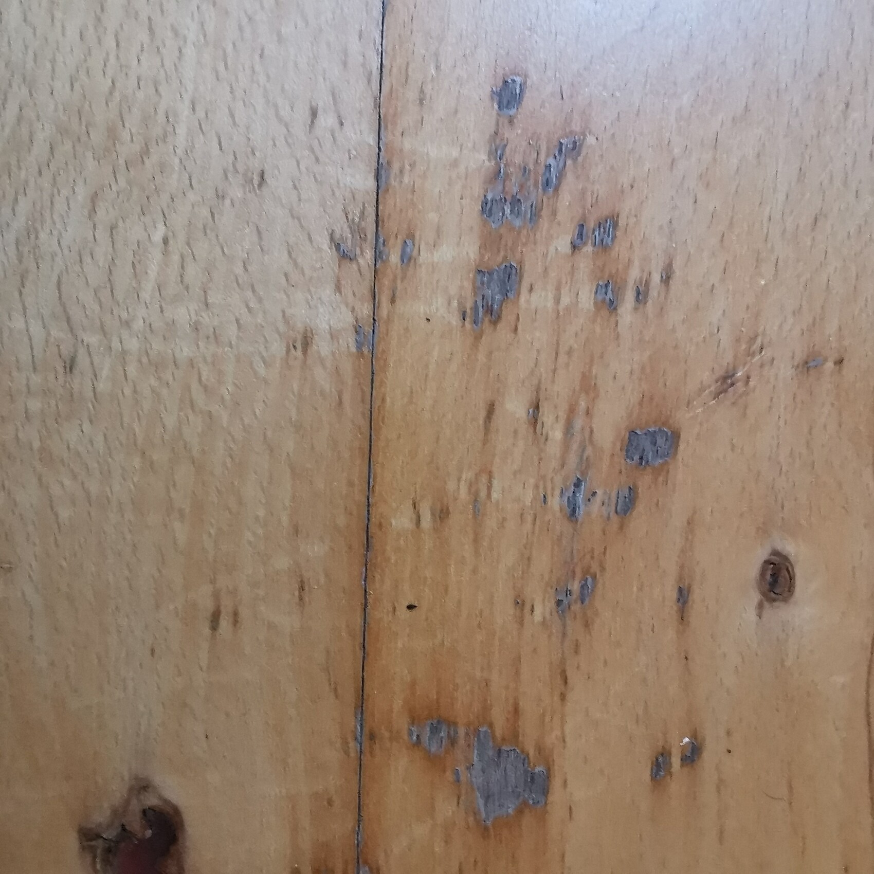 Holzplanken mit abplatzender Farbe, sichtbare Maserung und Knoten