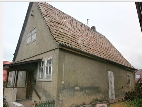 Außenansicht eines alten Hauses mit schrägem Ziegeldach und Eingangstür