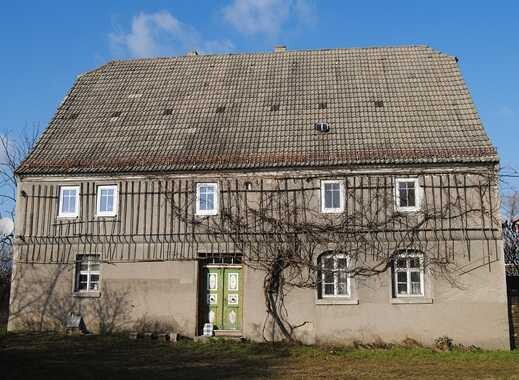 Zweistöckiges Haus mit grünem Eingang, rankende Weinreben an der Fassade, blauer Himmel