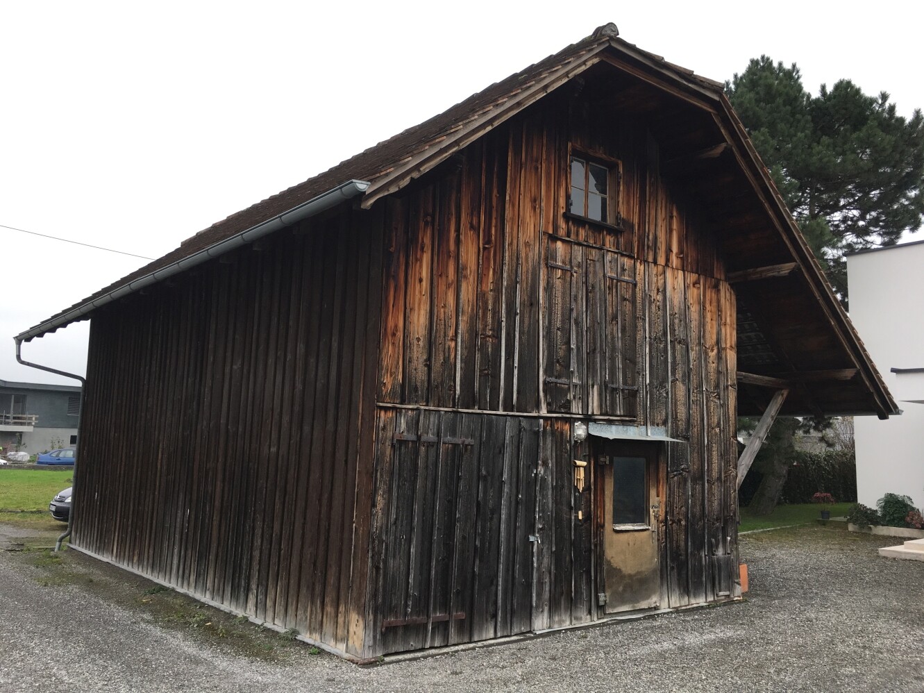Außenansicht eines alten Holzhäuschens mit Tür und kleinem Fenster