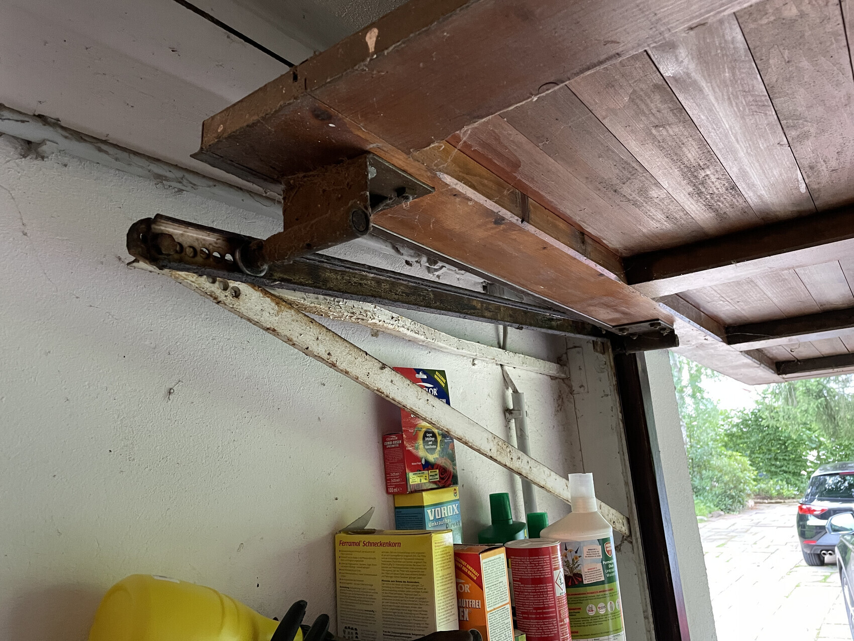 Verrostete Decken-Hebevorrichtung über Regal mit Reinigungsmitteln in der Garage.