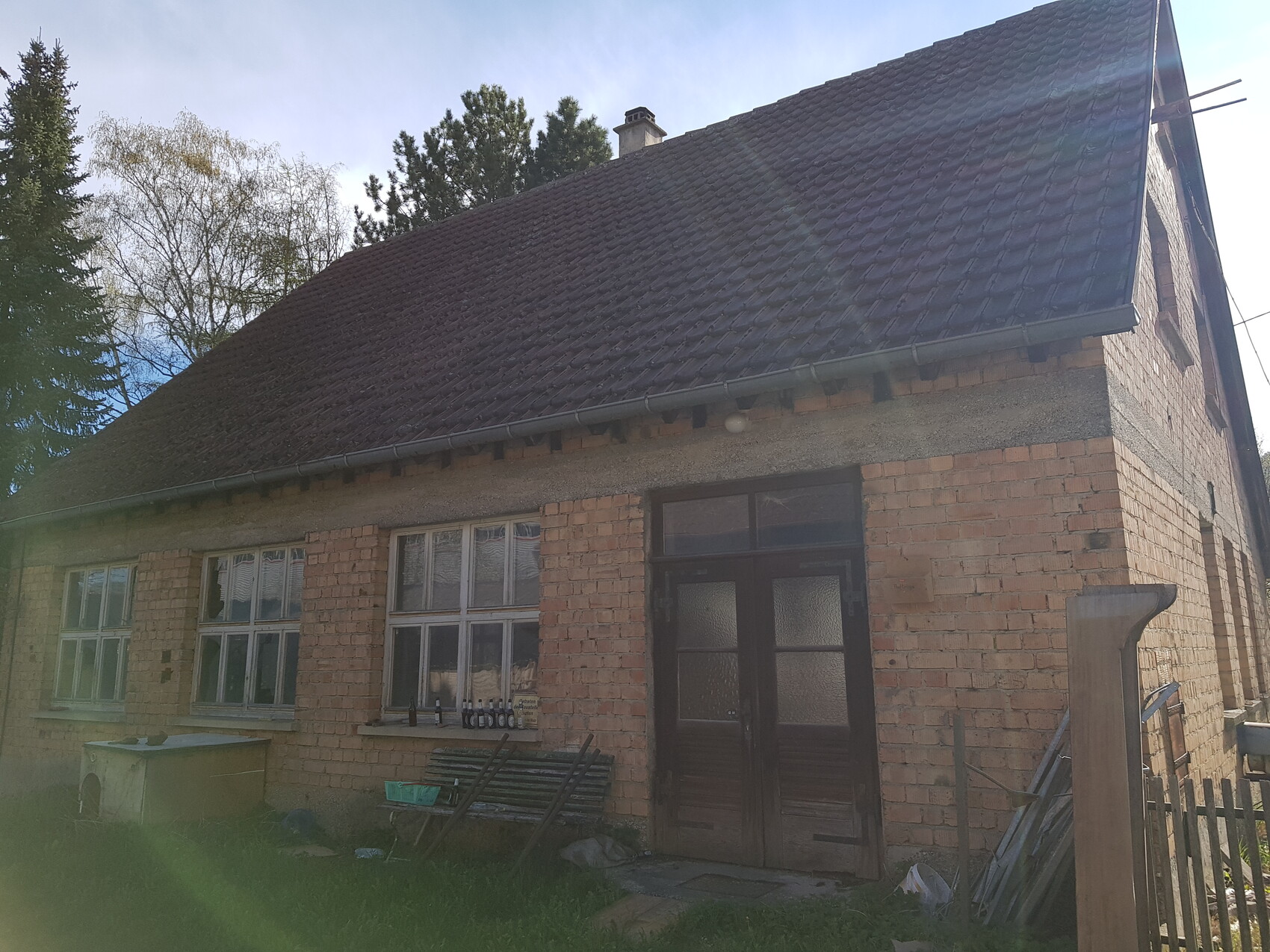 Außenansicht eines bemauerten Hauses mit dunkler Eingangstür und Dachziegeln