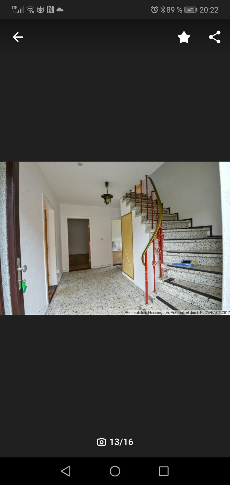 Heller Flur mit Treppe rechts, rotes Treppengeländer, Terrazzo-Boden, offene Türen.