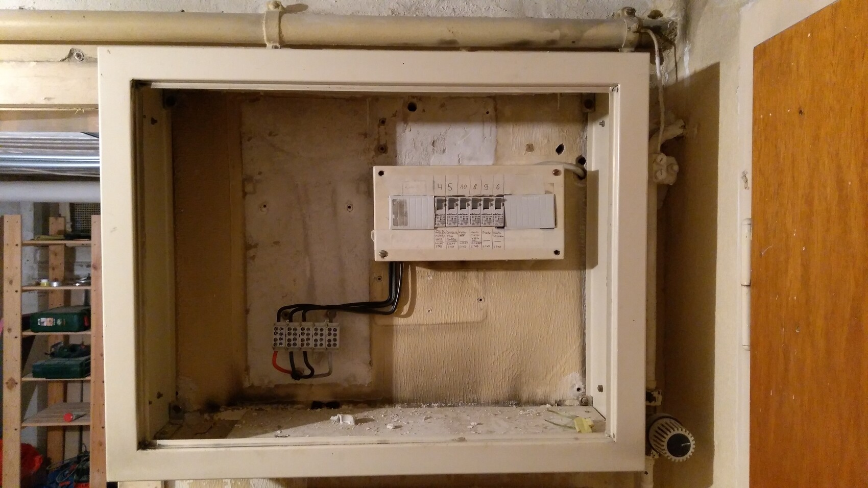 Offener Stromverteiler in Wandnische, Kabelbündel und Klemmblock, staubig und alt.
