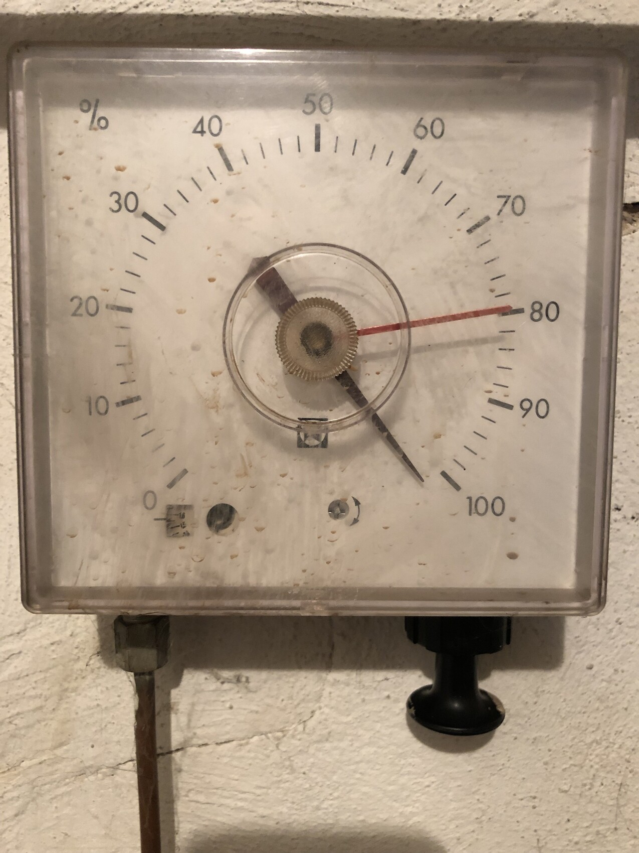 Altes analoges Messgerät mit 0–100% Skala; rote Nadel ca. 80% und schwarzer Zeiger.