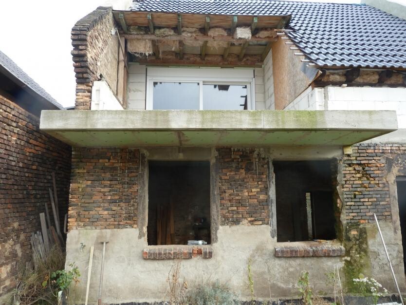 Verlassene Ziegelbau-Ruine mit offenem Fenster und Betonbalkon