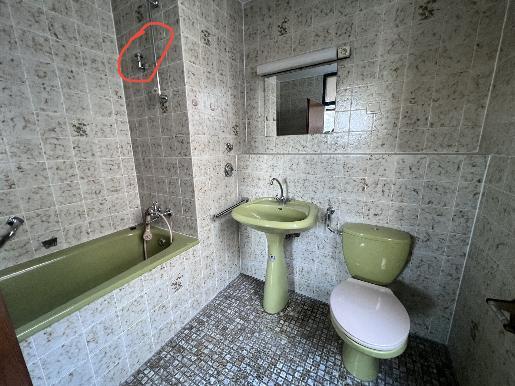 Altes Badezimmer mit grüner Badewanne, Waschbecken und Toilette, beige Fliesen