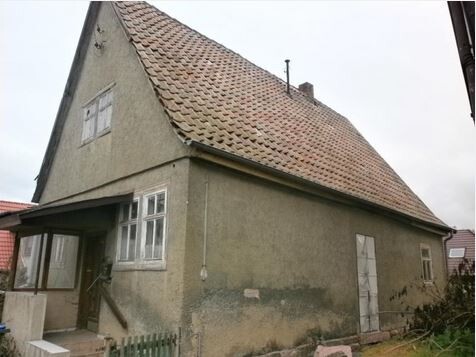 Außenansicht eines alten grün verputzten Hauses mit rotem Ziegeldach und Treppenstufen