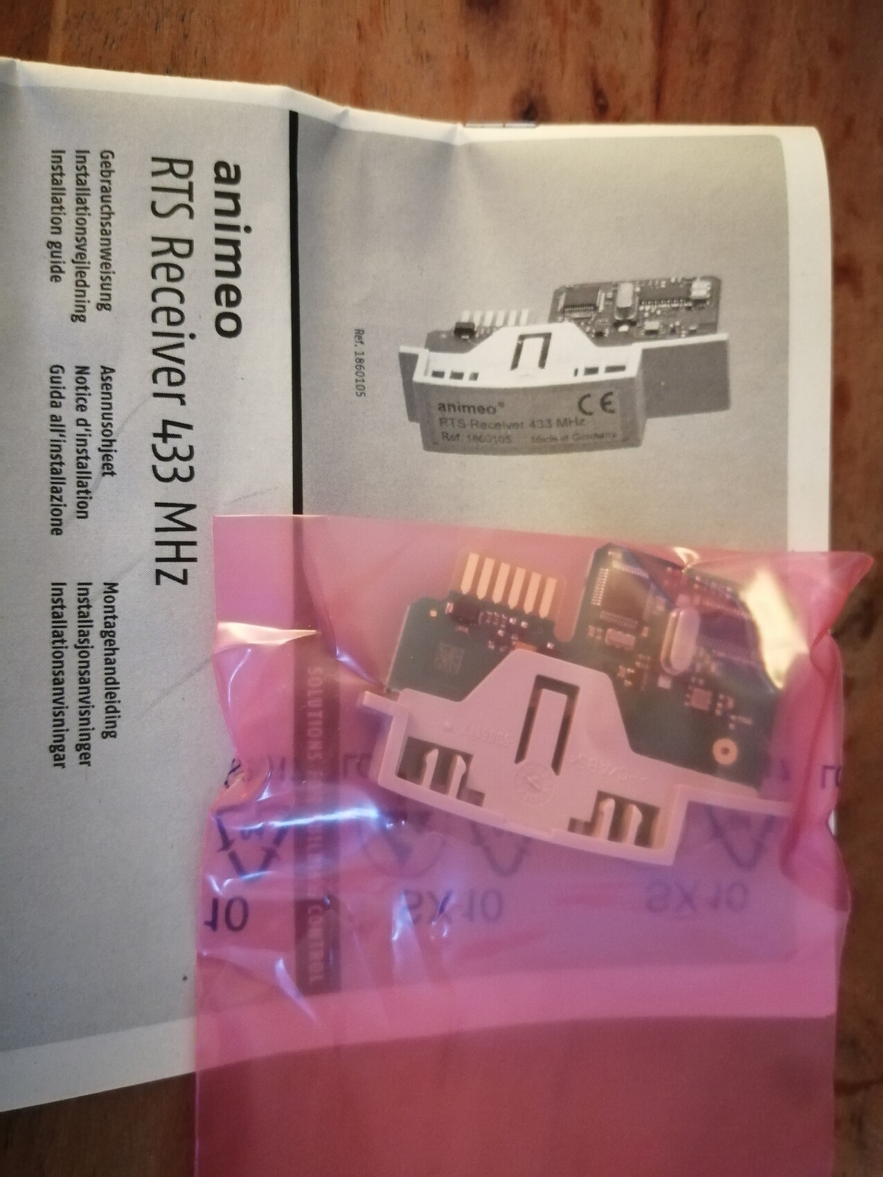 Kleines RF-Receiver-Modul in pinkem Antistatikbeutel neben Anleitung (animeo) 433 MHz.