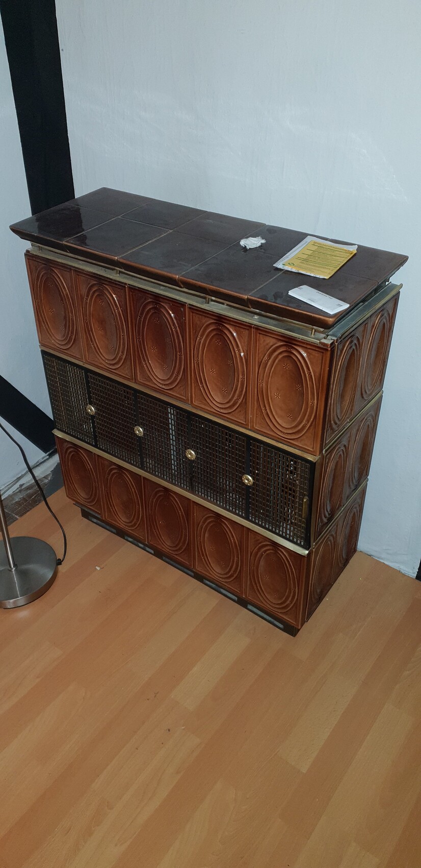 Vintage brauner Keramikschrank mit kreisförmigen Motiven, Gitterfronten, auf Holzboden.