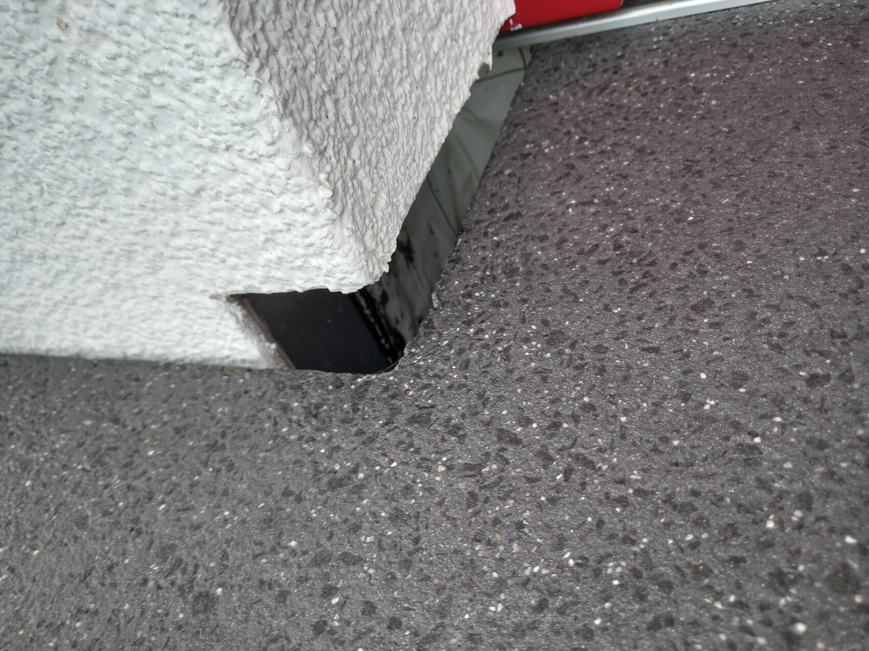 Außenwand mit rauer Putzstruktur und rechteckiger Öffnung zum dunklen Innenraum.