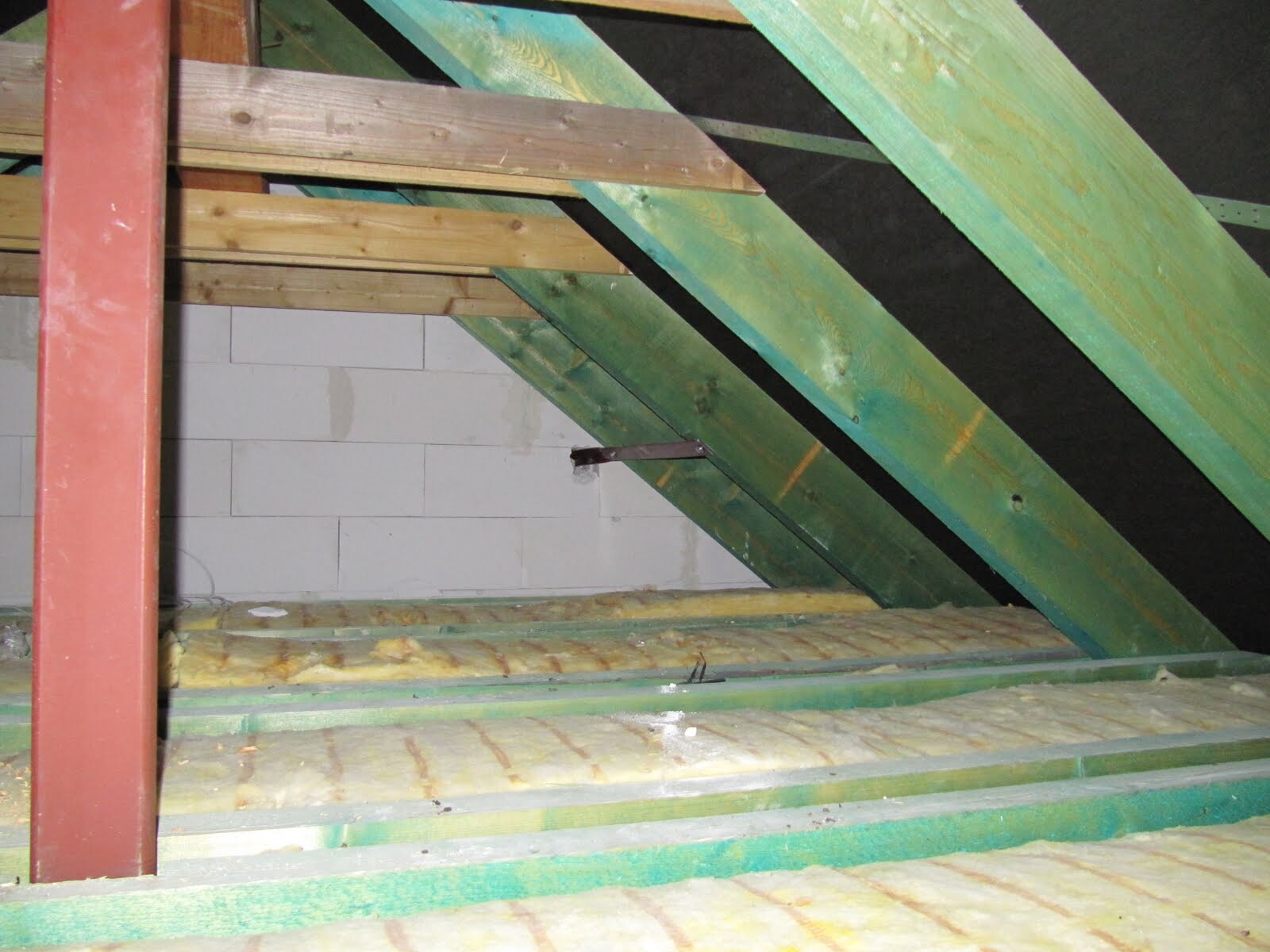 Dachstuhl aus Balken im unbeheizten Dachgeschoss mit Isolierung und Bauteilen