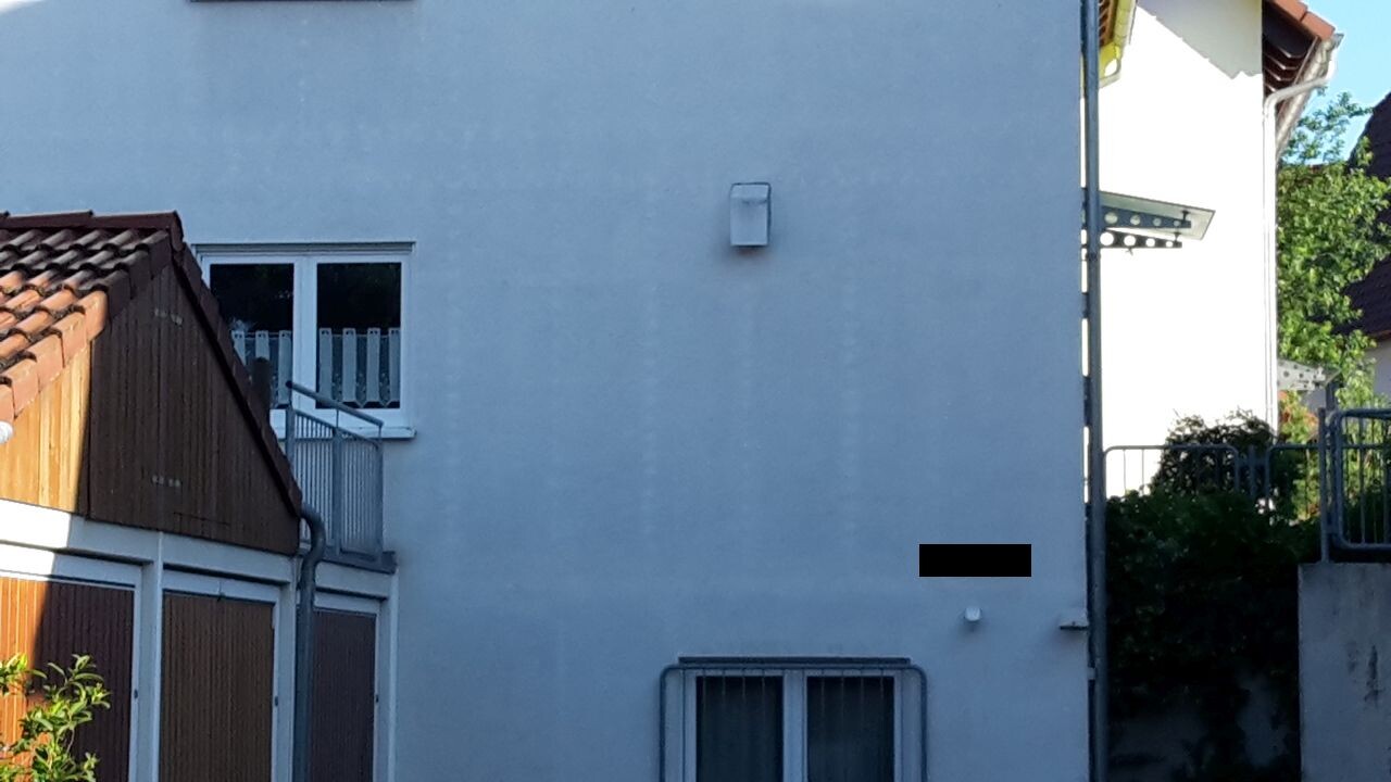 Außenansicht eines weißen Mehrfamilienhauses mit Fenstern und Balkon.