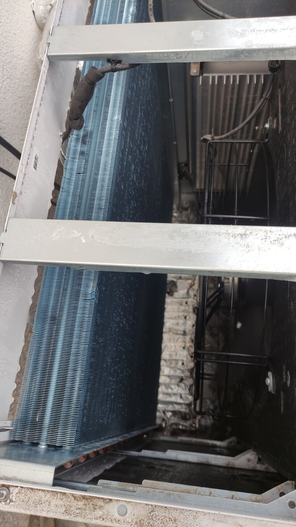 Nahaufnahme eines Klimageräts mit blauem Lamellen-Kühlkörper, Metallrahmen und Innenraum.