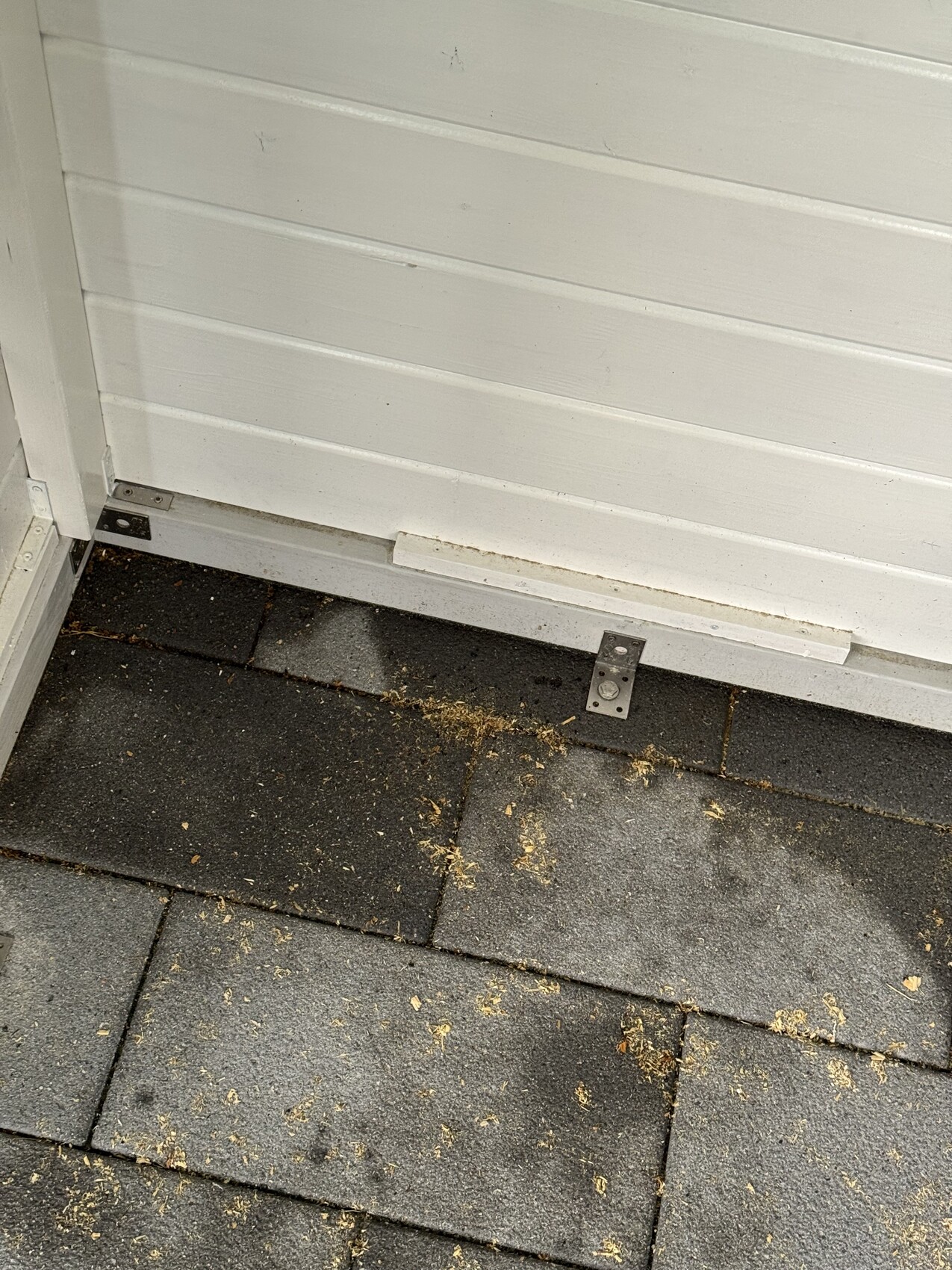 Außentür-Schwelle mit Metallhalterung vor dunklen Terrassenfliesen.