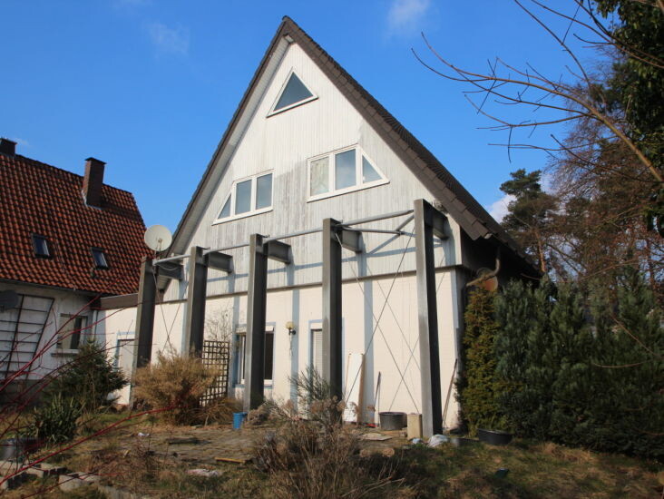Außenansicht eines Hauses mit Gerüst, Baumaterialien und Garten im Vordergrund