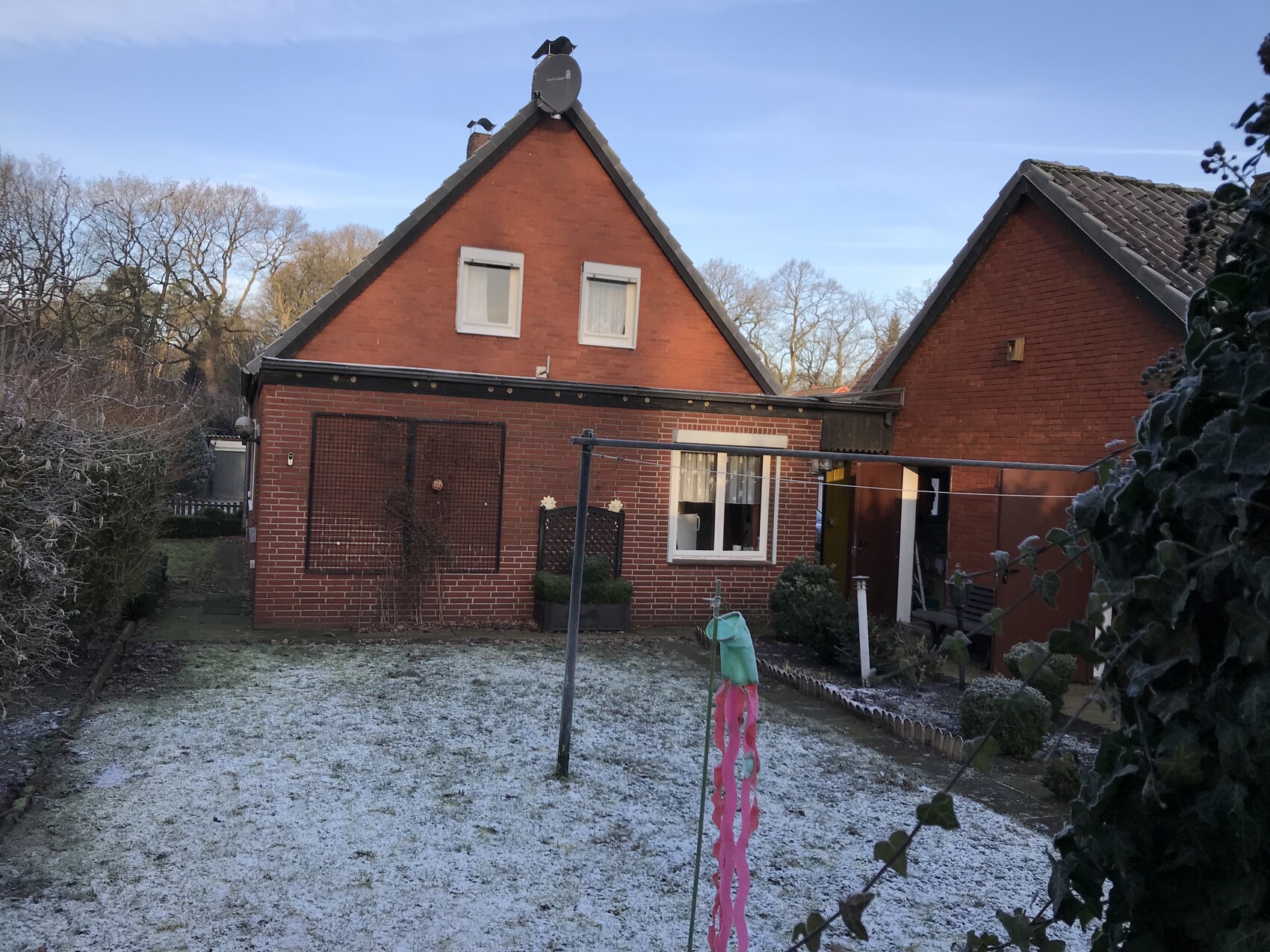 Rotes Ziegelhaus mit Satteldächern, Vorgarten und frostigem Rasen.