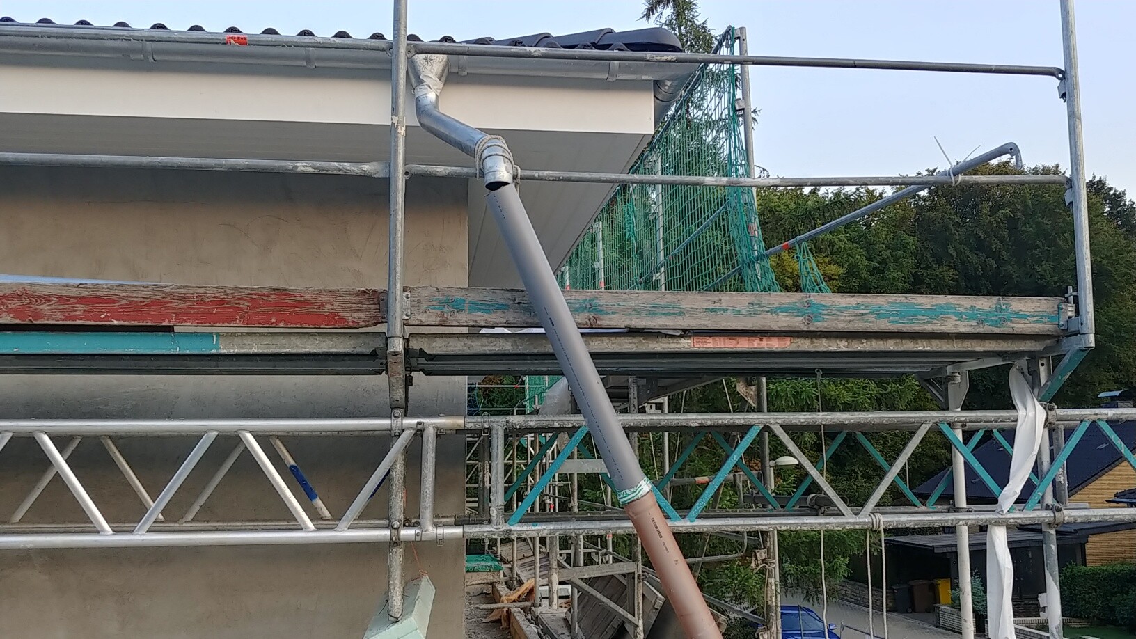 Außenbaustelle am Haus mit Gerüst, Dachrinne und Schutznetz