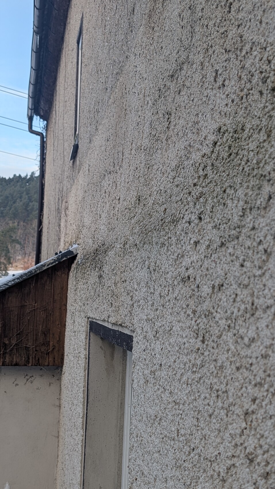 Aussenwand mit rauer putzoberflaeche, kleines Fenster sichtbar