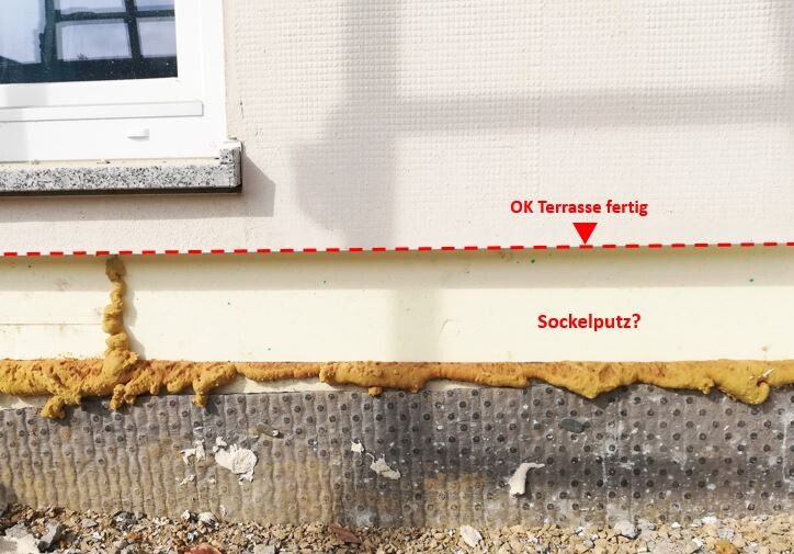 Außenwand mit Fenster; bröckelnder Sockelputz, Dämmung sichtbar, rote Linie markiert OK Terrasse.