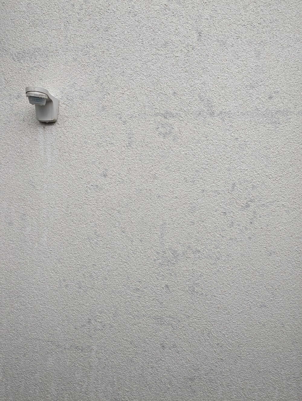 Außenwand mit texturierter Oberfläche und seitlich montierter Wandlampe