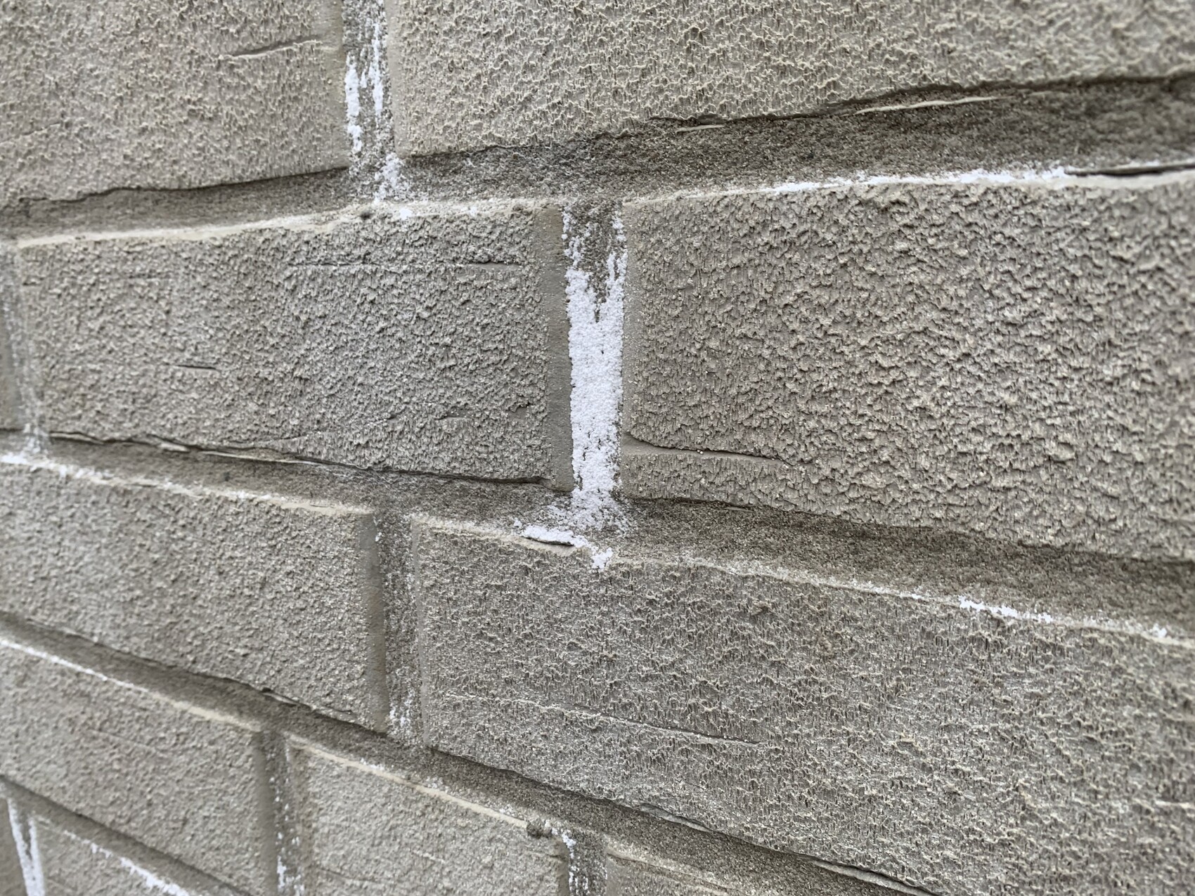 Nahaufnahme einer grauen Betonsteinmauer mit rauer Oberfläche und weißen Fugen