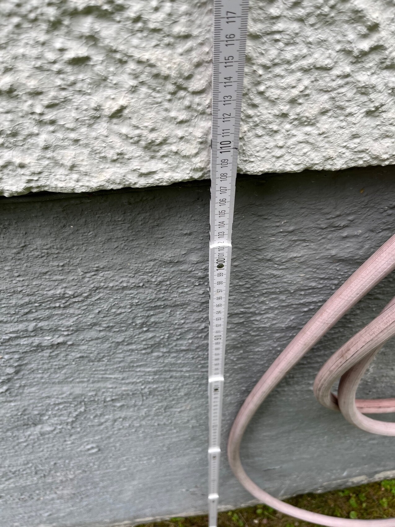 Messband an rauer Außenwand zeigt Messung am Fundament eines Hauses