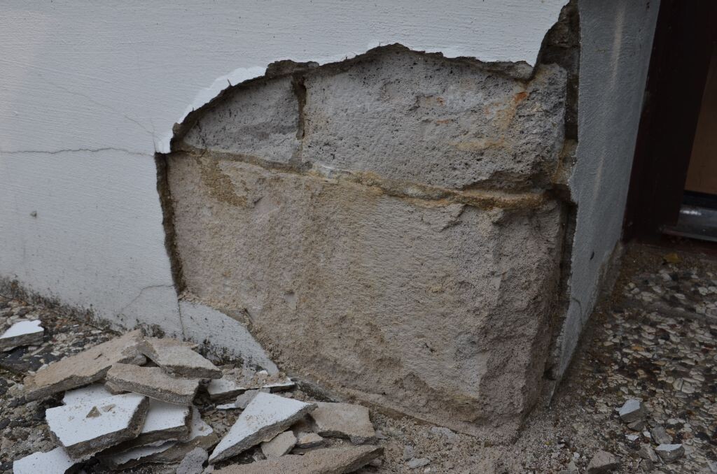 Aussenwand mit Putzschaden, lose Putzreste und Bauabfall am Fundamentbereich