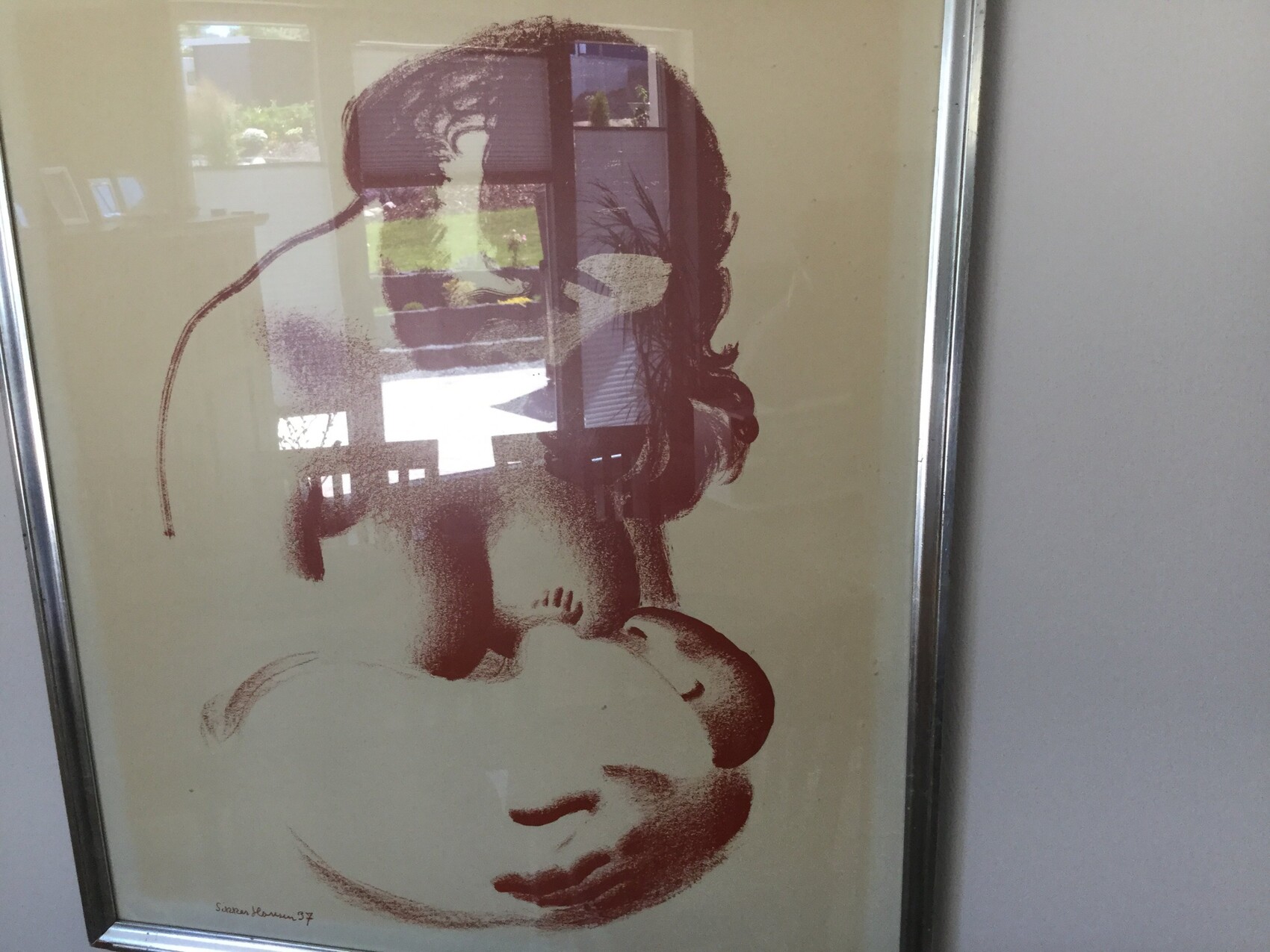 Roter Kunstdruck eines schlafenden Babys in einem Rahmen, Glas reflektiert den Innenraum.