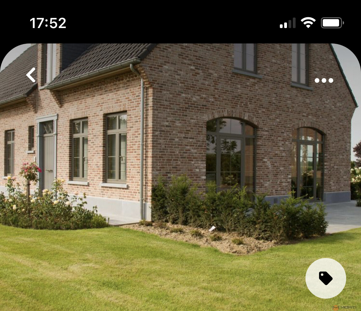 Ziegelhaus mit großen Fenstern und Garten vor grünem Rasen