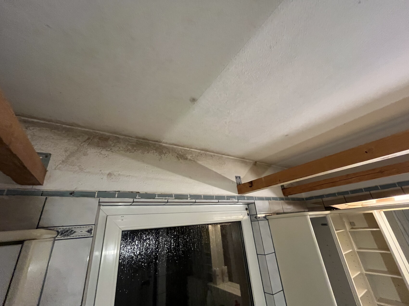 Badezimmer-Decke mit Holzbalken, Fliesenwand und Fenster, Renovierungsbedarf sichtbar