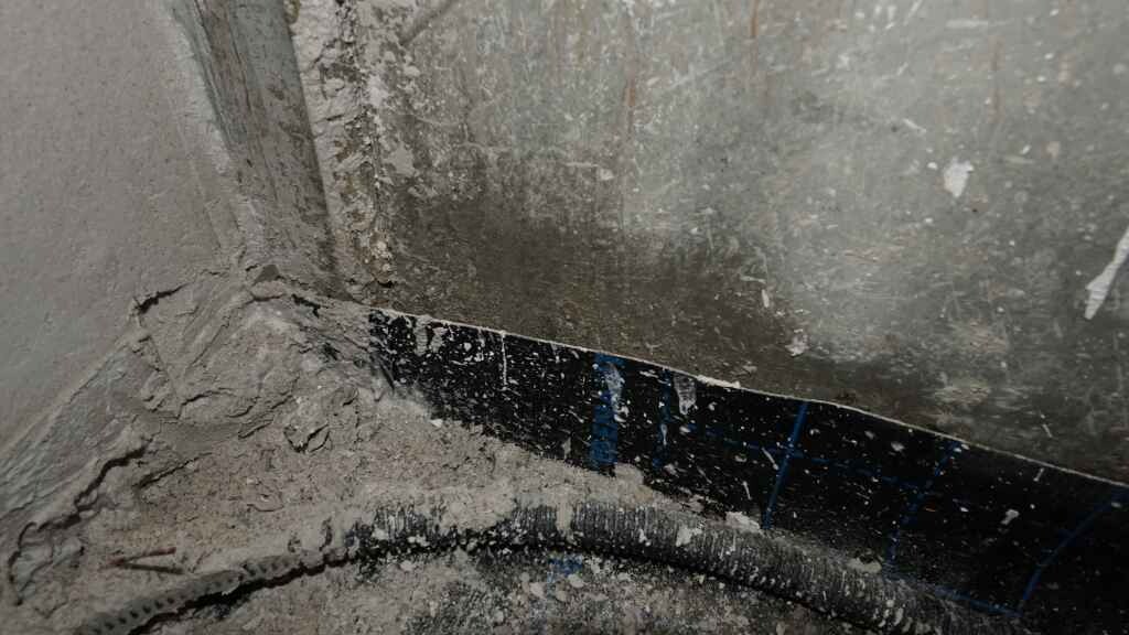 Baustelle Badezimmer: rohe Wand, unvollendete Fliesenverlegung, Staub auf dem Boden