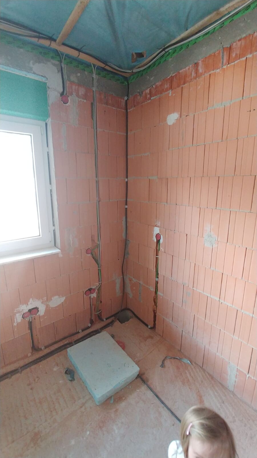 Unverputzter Badezimmer-Rohbau mit sichtbaren Wasserleitungen und Elektroverkabelung