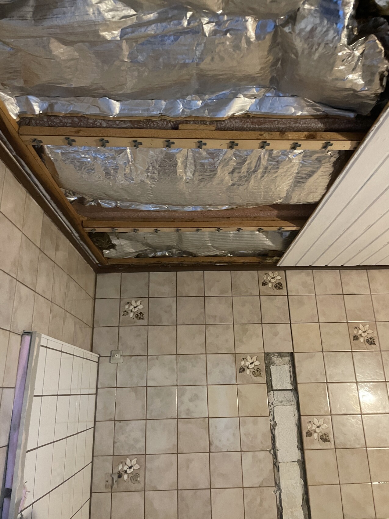 Badezimmer im Ausbau: offene Decke mit Dämmung, Folie und Fliesenboden.